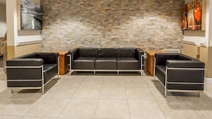Eine moderne Lobby mit Wand aus Steinmosaik, einer schwarzen Ledersofa und einem Holztisch.