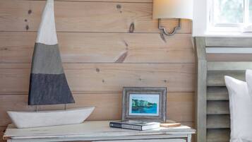Eine rustikale Holzwand mit einem gerahmten Bild, ein weißer Tisch mit einem Buch mit dem Titel 'Vögel Neuenglands' und eine kegelförmige Skulptur.