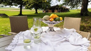 Une table dressée à l’extérieur, avec une carafe, des verres et un saladier rempli de fruits.