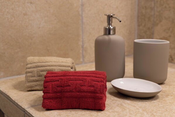 A bathroom counter with a beige towel, a red towel, a soap dispenser, and a soap dish.