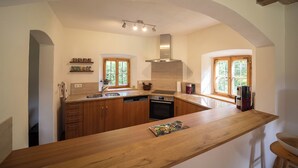 Une cuisine avec des meubles de rangement en bois, un îlot central et un four encastré.