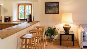 Une cuisine avec des tabourets en bois, une table avec une lampe et un tableau accroché au mur.