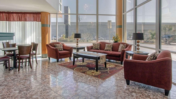 A spacious lobby with a large window, a dining area, and a seating area with sofas and a coffee table. - Rodeway Inn Central Clearwater Beach (Clearwater)