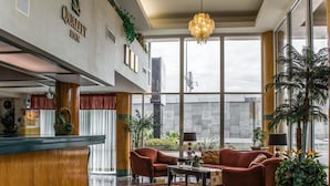 A hotel lobby with a reception desk, a seating area with a sofa and armchairs, a chandelier, and large windows offering a view of the outside. - Rodeway Inn Central Clearwater Beach (Clearwater)
