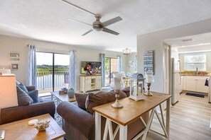 A spacious living area with a balcony, a dining table, and a kitchen area.
