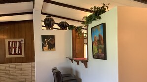 A room with a wooden ceiling, a stone wall, a black leather chair, a wooden shelf with a plant, and two framed artworks. - Neat Retreat, Fast WiFi, Ski Sipapu, Hike, Fish, Hunt,
Wineries, pet friendly  (Penasco)