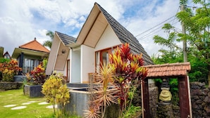 A modern house with a sloped roof, a small porch, and a garden with various plants. - Break Villa Kintamani (Kintamani)