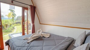 A bedroom with a bed, a view of a garden, and a ceiling with a wooden panel design. - Break Villa Kintamani (Kintamani)
