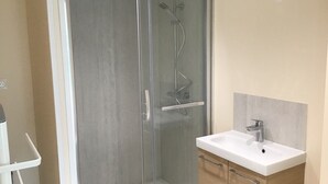 Un bagno moderno con doccia vetrata, lavandino bianco e mobili in legno.