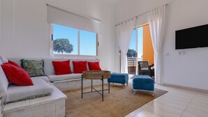 A living room with a sofa, ottoman, and a round table. - Accommodation "Tucanes" with Terrace and Wi-Fi (Corralejo)