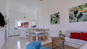 A modern living room with a dining area, white walls, and tropical-themed artwork. - Accommodation "Tucanes" with Terrace and Wi-Fi (Corralejo)