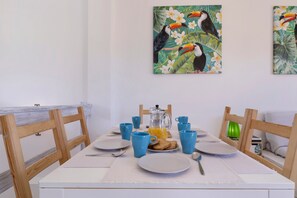 A dining table set with plates, cups, and a pitcher, surrounded by wooden chairs.