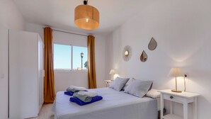 A bedroom with a bed, bedside tables, a window with curtains, and wall decorations. - Accommodation "Tucanes" with Terrace and Wi-Fi (Corralejo)