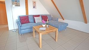 Ein gemütliches Wohnzimmer mit einem blauen Sofa, einem Holztisch und einer kleinen Dekoschale.