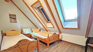 A bedroom with two wooden beds, a skylight, and a view of the sky.