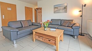 A modern living room with two grey sofas, a wooden coffee table, and a painting on the wall.