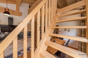 Una escalera de madera con una cocina moderna al fondo.