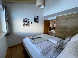 Un dormitorio con una cama, un armario de madera y dos cuadros colgados en la pared.