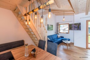 Et moderne interiør med en trætrap, en blå sofa, et spisebord og hængende lysarmaturer.