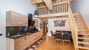 Eine moderne Küche mit Holzschränken, einer schwarzen Arbeitsplatte und einem Essbereich mit einem Holztisch und Stühlen.