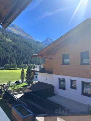 A modern two-story building with a flat roof, large windows, and a view of a mountainous landscape. - Apartment Enzian - TUX MOUNTAIN apart (Juns)