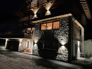 Un immeuble de deux étages avec une façade en pierre, un balcon et une entrée éclairée.