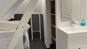 A modern bathroom with a white sink, mirror, and dark tiled floor. - Adorable apartment located in a castle (AVOINE)