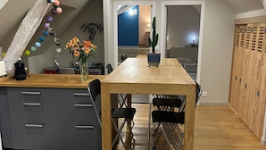 A modern kitchen with a wooden table, grey cabinets, and a patterned floor. - Adorable apartment located in a castle (AVOINE)