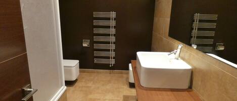 A modern bathroom with a white sink, a mirror, and a towel rack.