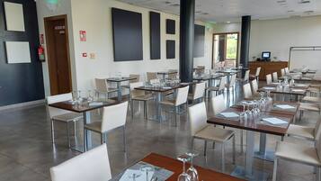 A dining area with multiple tables set for service, equipped with wine glasses and cutlery.