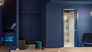 A bedroom with a bed, a desk, a chair, a wardrobe, and a bathroom with a shower and a towel rack. - Apartment with Hotel treatment (SIRACUSA)