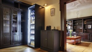 A room with wooden flooring, a dark wooden cabinet, a glass-fronted beverage refrigerator, and a small table with a vase. - Hotel Wiener Botschaft (Veitshoechheim)