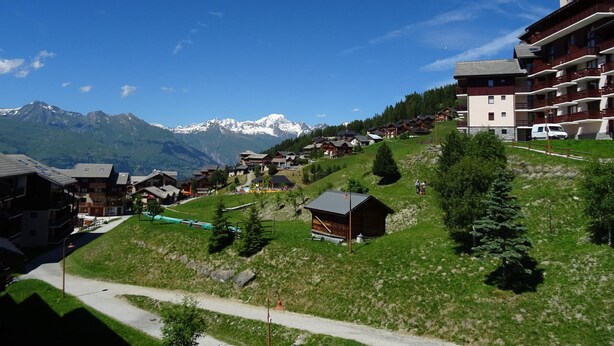 Un pueblo de montaña con casas de madera tradicionales, una cabaña de madera y vistas a montañas nevadas.