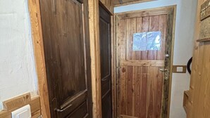 Una puerta de madera con un ventanal, un timbre y un interruptor de luz en la pared.
