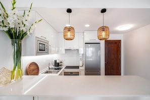 A modern kitchen with white cabinetry, a stainless steel refrigerator, and a wooden door.