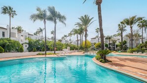 A swimming pool surrounded by palm trees and white buildings.