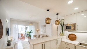 A modern kitchen with white cabinetry, a central island, pendant lighting, and a built-in microwave.