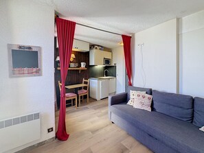 A compact living space with a kitchenette, a sofa, and a dining area.