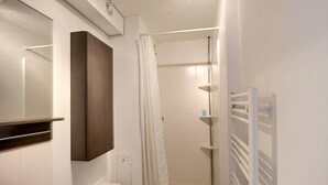 Un baño pequeño con inodoro, lavamanos, espejo y zona de ducha.