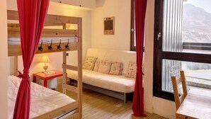 Una habitación acogedora con literas, un sofá y una ventana con vistas a montañas.