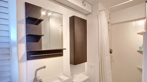 Un baño con lavamanos, espejo, armario, inodoro y cortina de ducha.