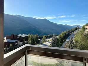 A balcony with a view of a mountain range and a parking area.