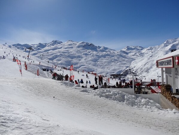 Pista de esqui coberta por neve, com um teleférico e um edifício com um letreiro.
