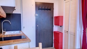 Una cocina compacta con un lavabo, una estufa y una silla de madera.