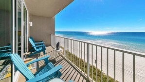 Ein Balkon mit blauen Stühlen und Blick auf den Strand.