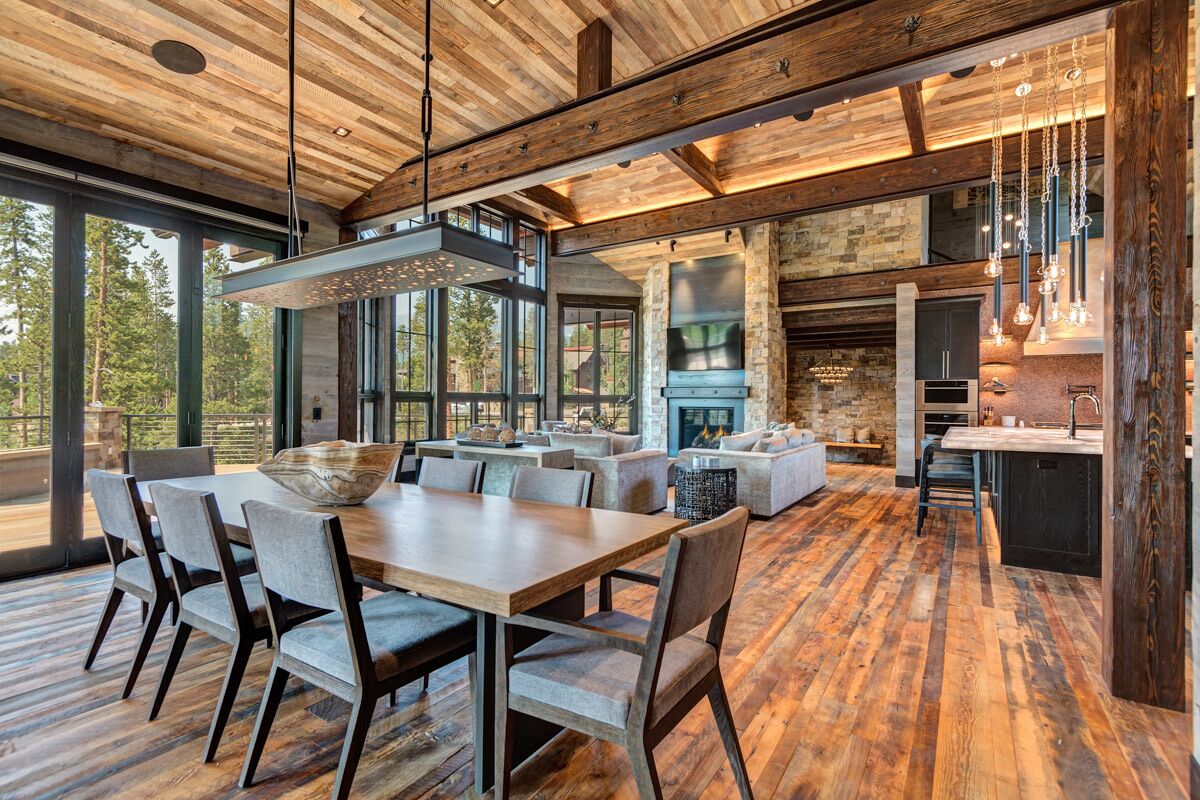 A spacious kitchen with a large island, stone fireplace, and hanging pendant lights.