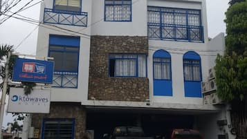 A two-story building with the sign 'ktowaves Hotel' on the facade. There are two vehicles parked in front, a black pickup truck and a red pickup truck.
