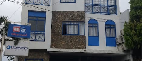 A two-story building with the sign 'ktowaves Hotel' on the facade. There are two vehicles parked in front, a black pickup truck and a red pickup truck.