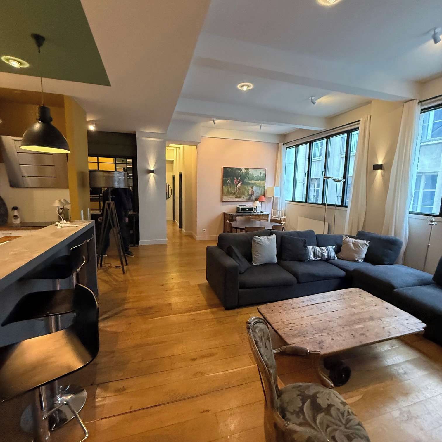 Un salon moderne comprenant un canapé, une table basse et un coin repas avec un bar.