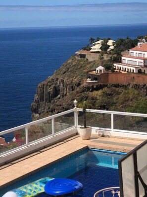 A pool with a view of the ocean and a building with a red roof. - VILLA HIBISKUS (Santa Úrsula)